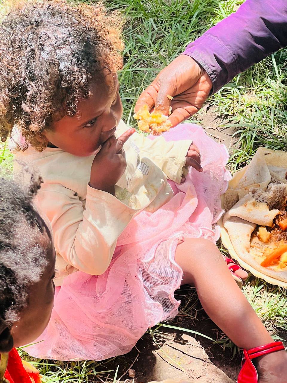 A volunteer feeding a young child by hand