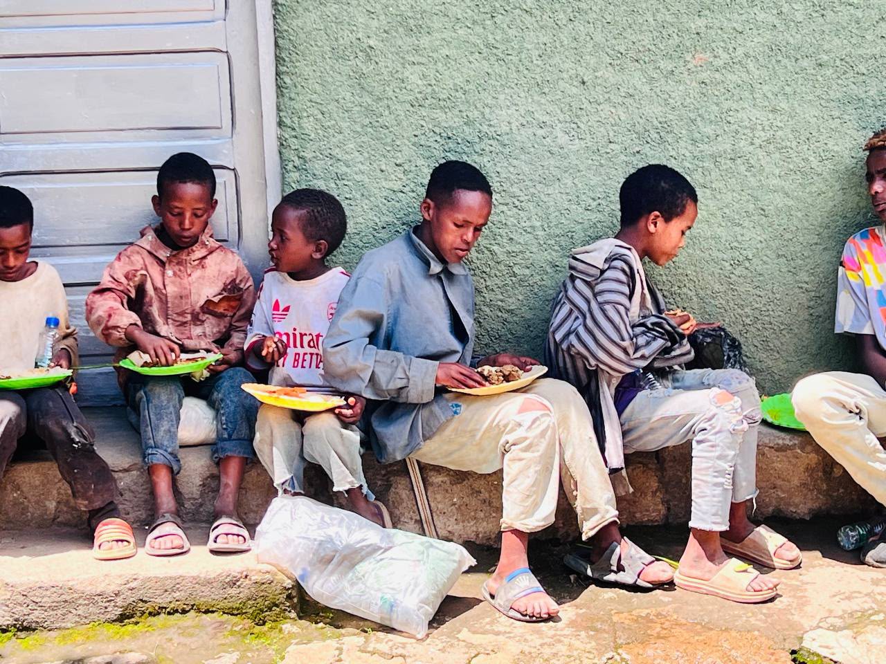 Children sitting on steps eating from plates