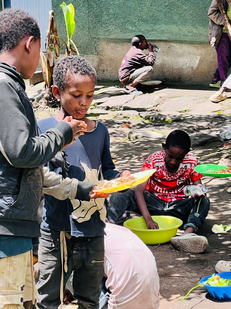 Volunteers serving food and washing dishes for children