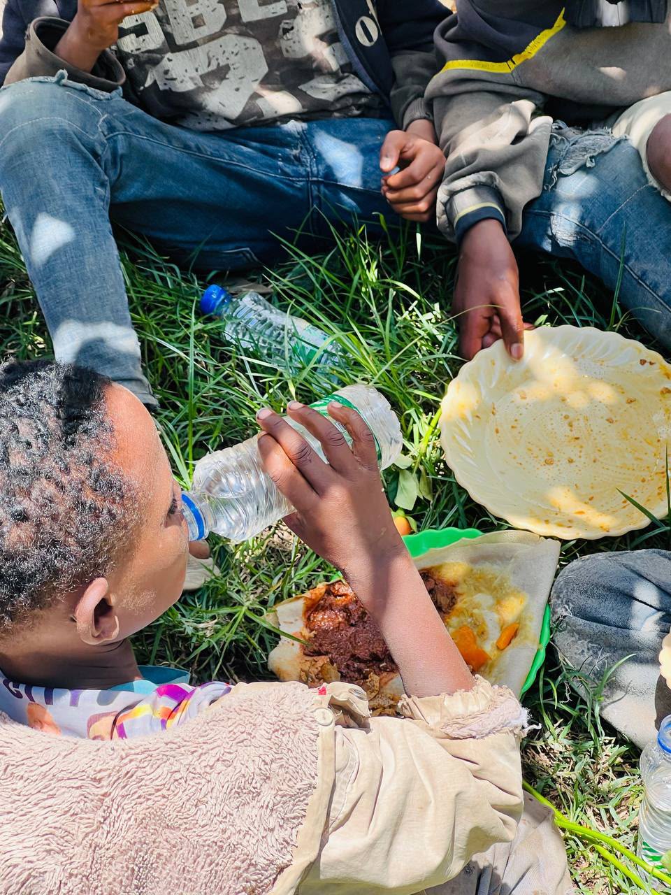 Child drinking water beside a plate of food