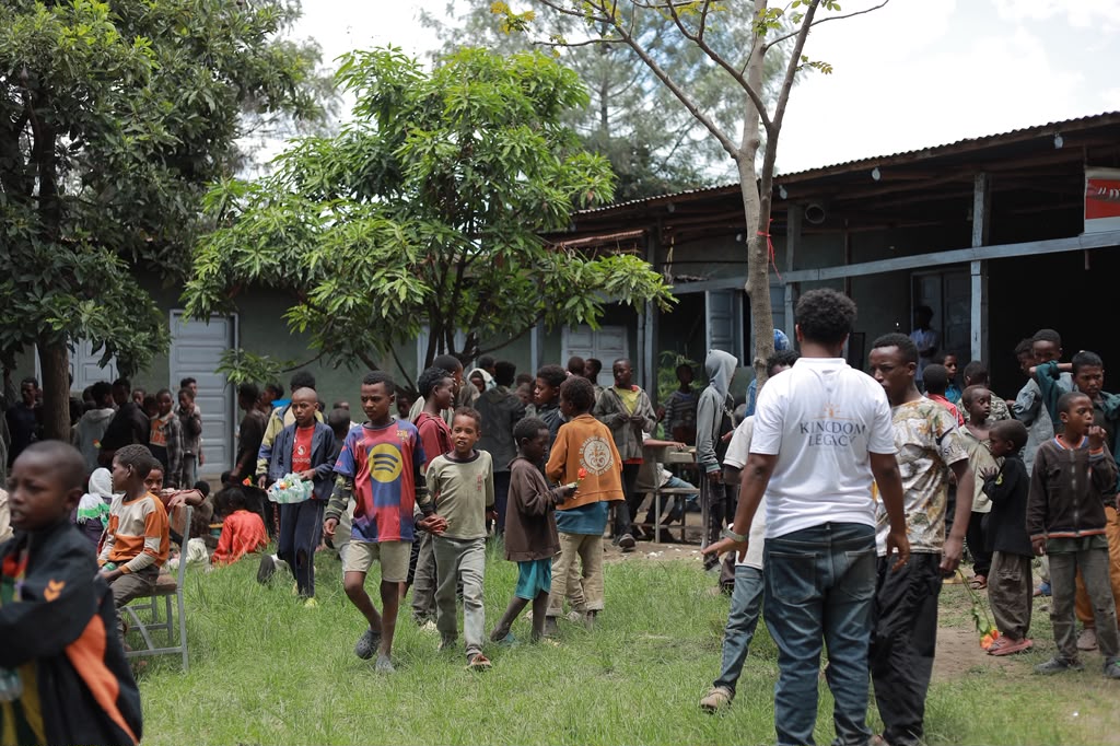 Crowd of children gathered outdoors with a Kingdom Legacy staff member