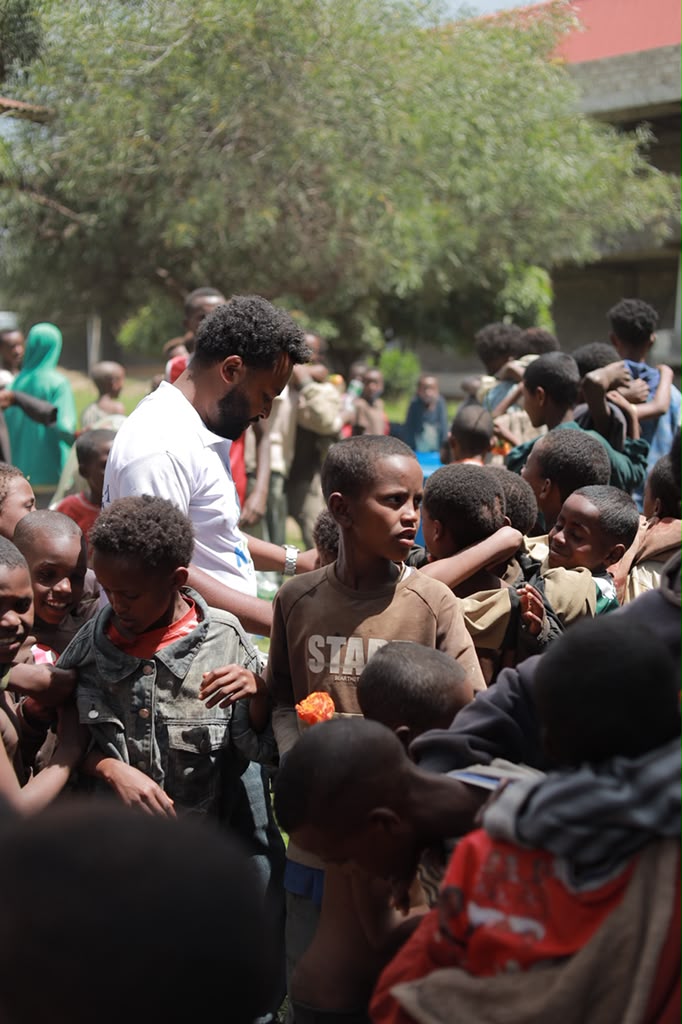 A volunteer surrounded by a crowd of children outdoors